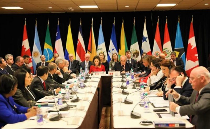 Foto ilustrativa sobre diplomáticos y diplomáticas. La foto muestra banderas y personas debatiendo. La imagen corresponde a una edición pasada de la llamada Cumbre de las Américas.